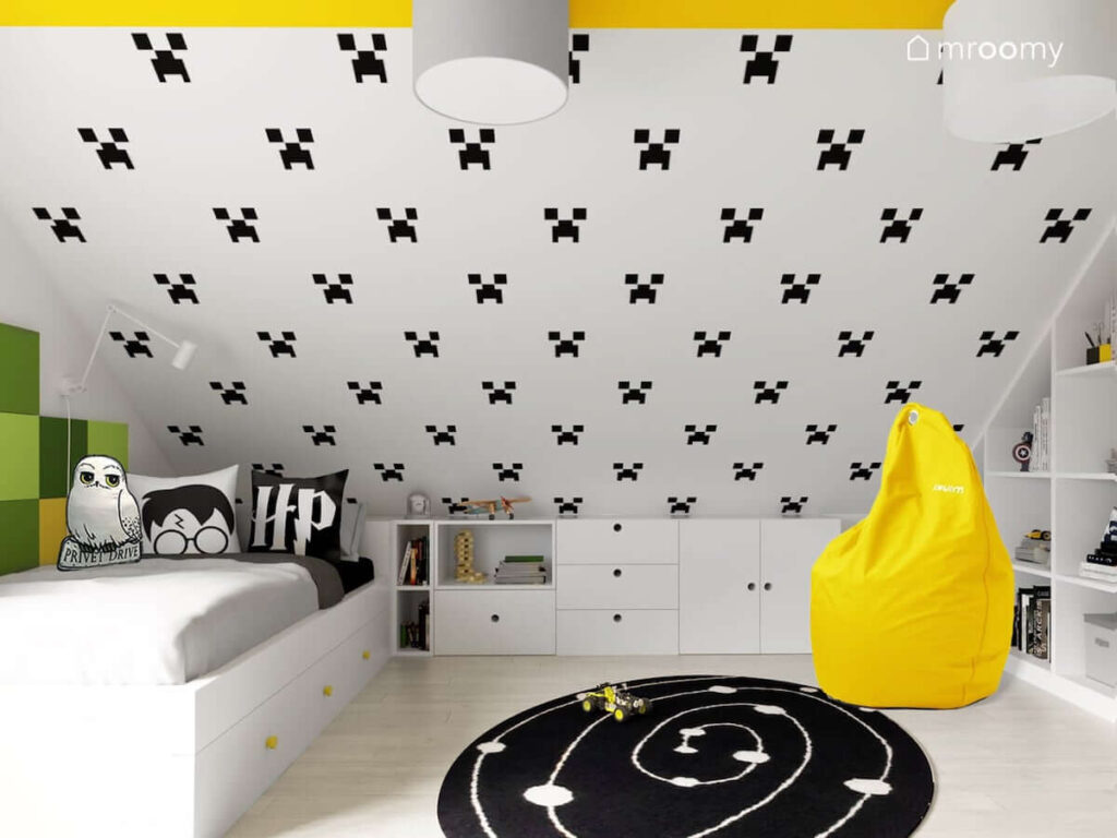 Pokój na poddaszu dla chłopca w kolorystyce biało-czarnej z żółtymi dodatkami z okrągłym czarnym dywanem z tapetą ze wzorem Minecraft