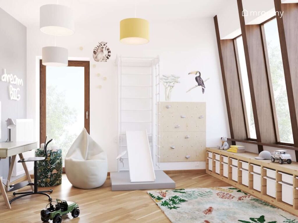 Jasny pokój dla chłopca z drewnianymi meblami oraz drabinką gimnastyczną i ścianką wspinaczkową a także naklejkami w kształcie zwierząt na ścianach i białym workiem sako