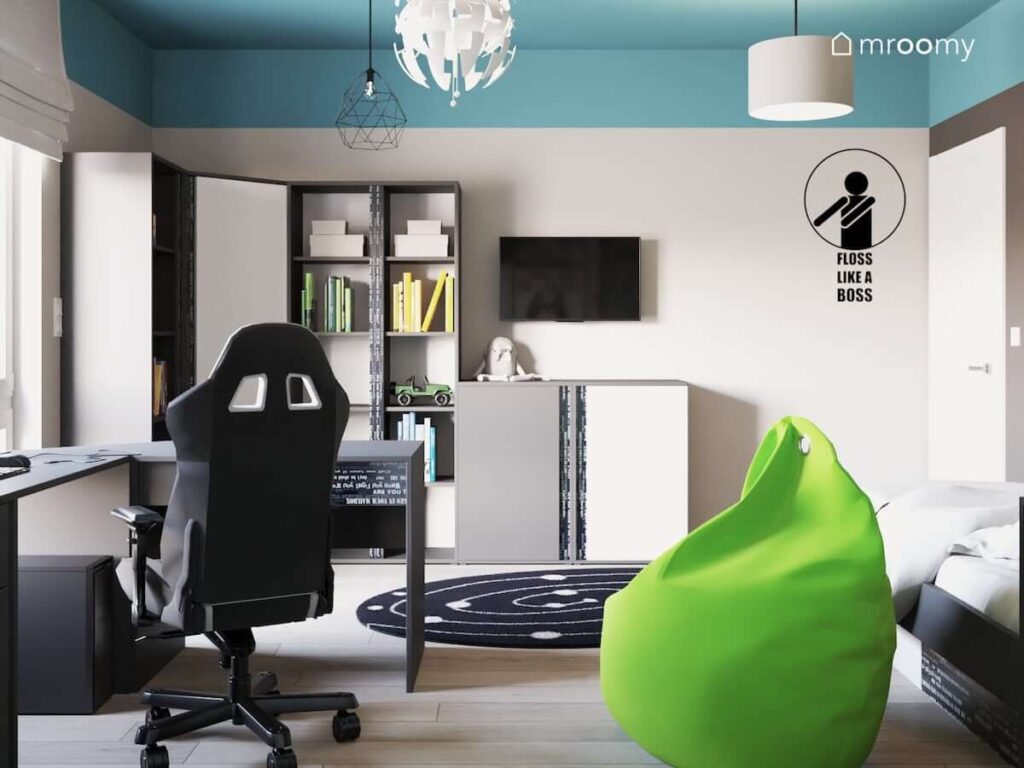 Pokój dla nastolatka fana gier komputerowych z biało-czarnymi meblami fotelem gamingowym zielonym workiem sako i turkusowym sufitem czarnym okrągłym dywanem