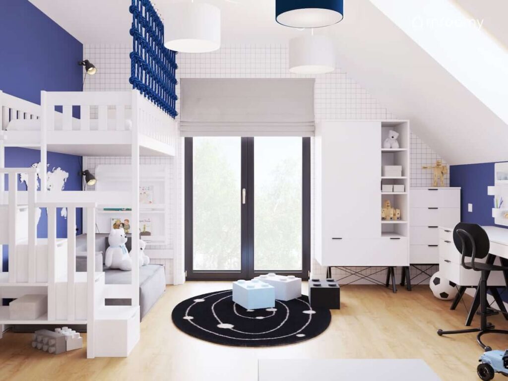Pokój dla chłopca z łóżkiem na antresoli z nowoczesnymi białymi meblami z czarnymi dodatkami z pufkami w kształcie klocków lego i czarnym okrągłym dywanem
