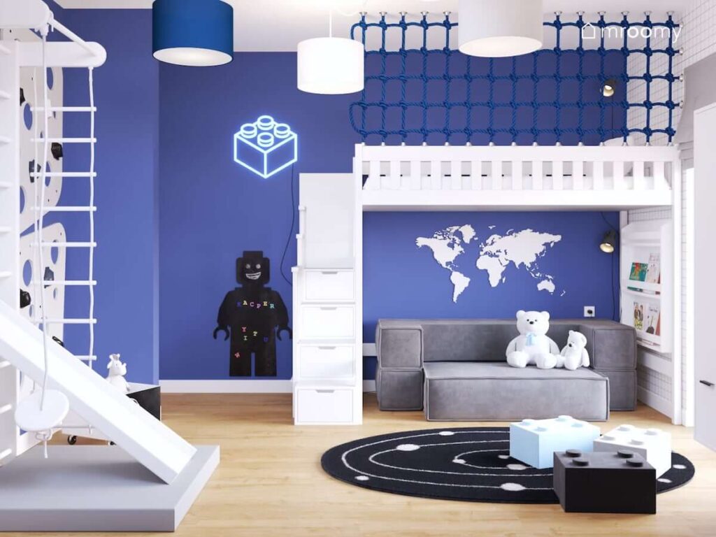 Niebiesko-biały pokój dla fana klocków lego z łóżkiem na antresoli z siatką zabezpieczającą drabinką gimnastyczną ledonem i tablicą magnetyczną w kształcie ludzika lego