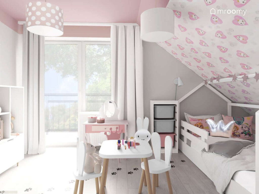 Dziewczęcy pokój w kolorystyce szaro-różowej z łóżkiem domkiem pod skosem stolikiem i krzesełkami z oparciem w kształcie uszu królika