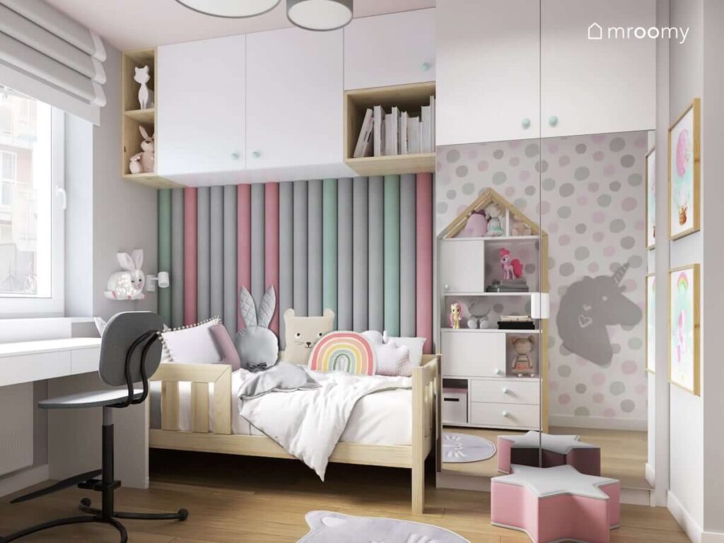 Pokój dla czterolatki w kolorystyce szaro-różowej z dodatkami w kolorze mięty z łóżkiem w kolorze naturalnego drewna z lustrem powiększającym optycznie wąski pokój z dywanem w kształcie pyszczka kota i miękkimi panelami przy łóżku