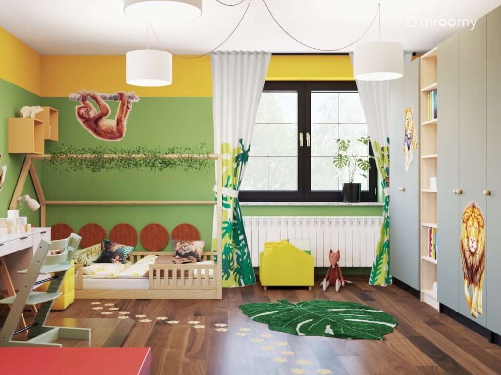 Kolorowy pokój dla dziewczynki z licznymi motywami dżungli oraz drewnianym łóżkiem w kształcie domku i dużymi szafami