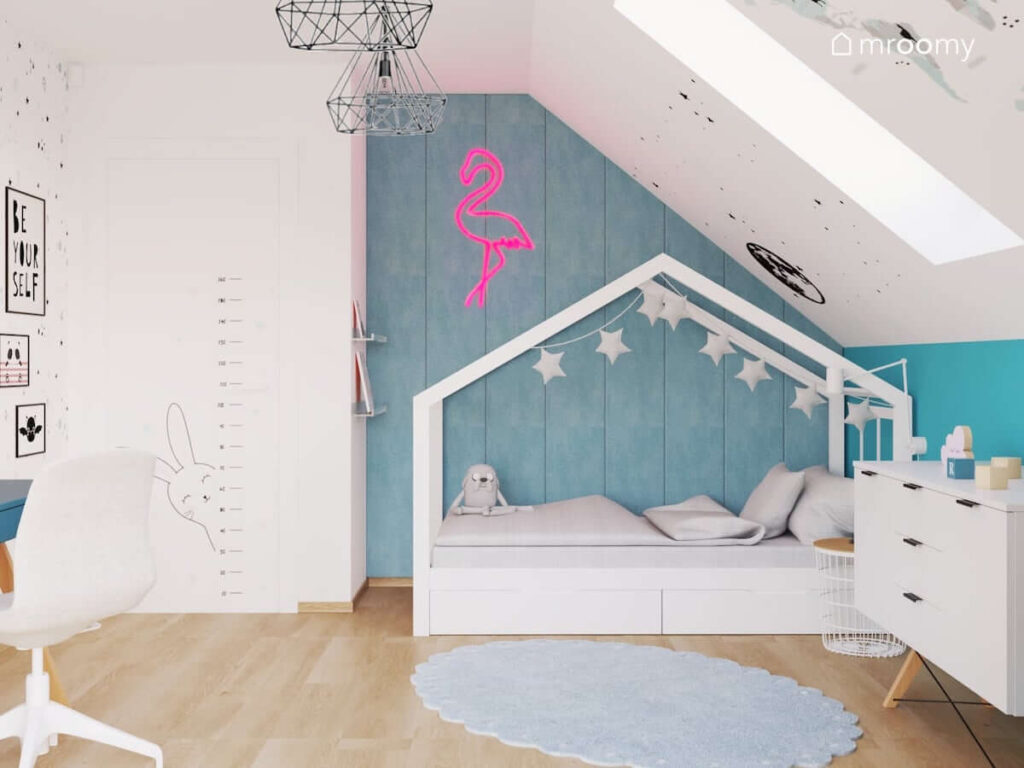 Biało niebieski pokój kilkulatki z łóżkiem w kształcie domku ozdobionym girlandą gwiezdną oraz z miarką wzrostu i różową lampą w kształcie flaminga
