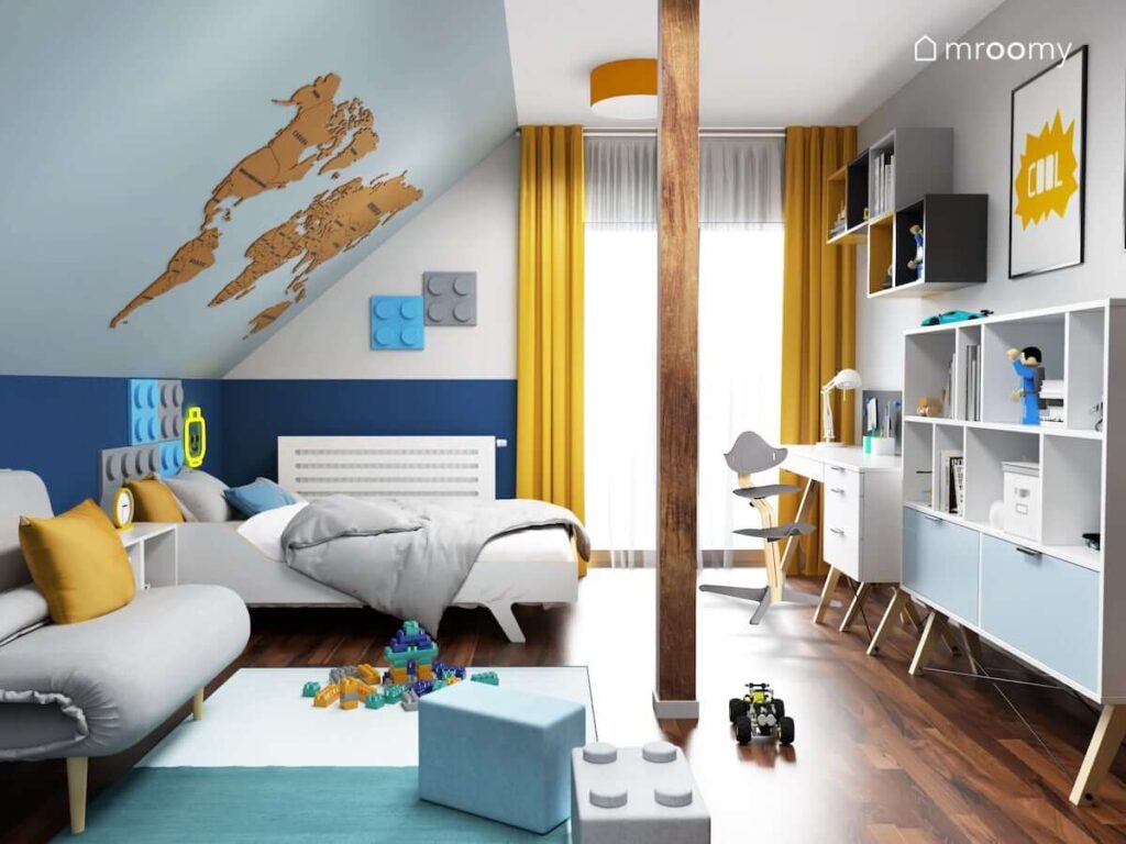 Biało szaro niebieski pokój dla chłopca z drewnianą mapą świata na skosie panelami ściennymi w kształcie klocków oraz białymi meblami i żółtymi dodatkami