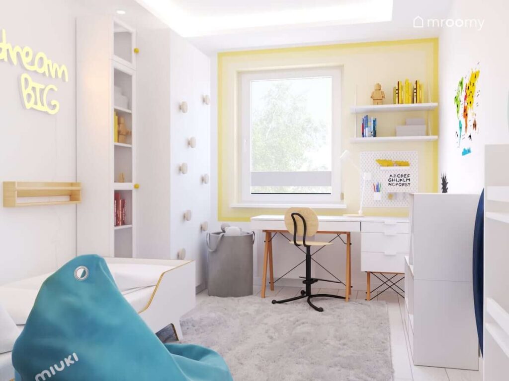 Biały pokój dla chłopca z białymi meblami z drewnianymi elementami szarym koszem na zabawki oraz niebieską pufą sako a także żółtym gradientem wokół okna