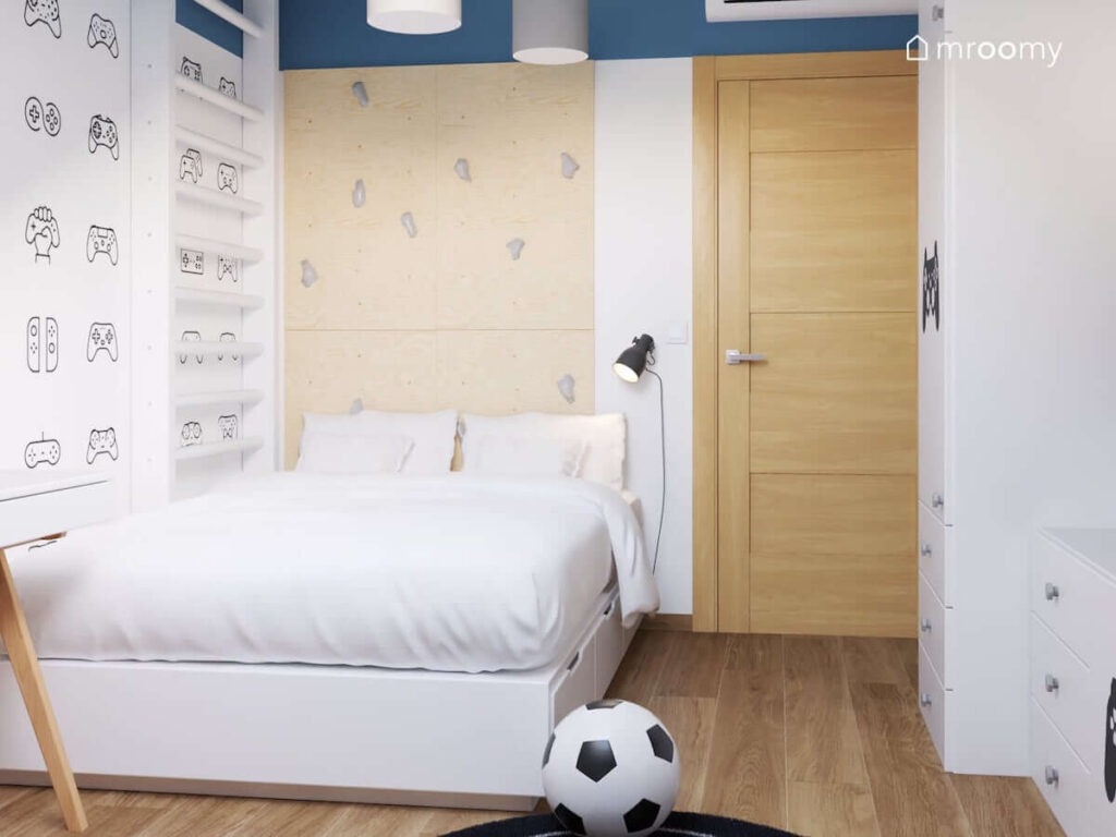 Białe łóżko oraz ścianka wspinaczkowa ze sklejki i drabinka gimnastyczna w pokoju dla chłopca w wieku szkolnym