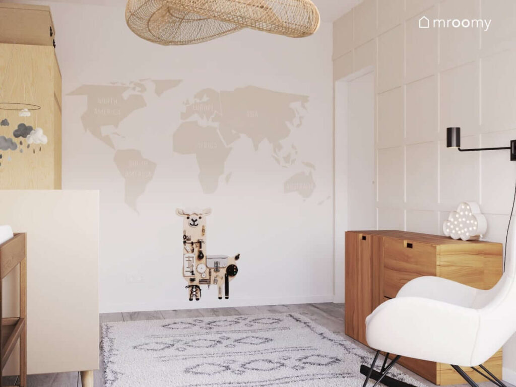 Beżowa tapeta z mapą świata tablica manipulacyjna w kształcie lamy oraz duży beżowy dywan w jasnym pokoju dla noworodka