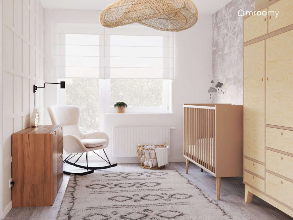 Pokój dla noworodka z drewnianym łóżeczkiem szafą ze sklejki a także bujanym fotelem i lampą sufitową w dużym naturalnym kloszu