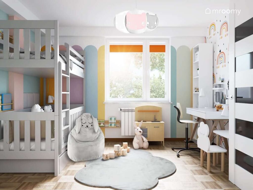 Pokój dla rodzeństwa z łóżkiem piętrowym fotelem w kształcie zająca oraz dywanem w kształcie chmurki oraz ścianą pomalowaną w różnokolorowe pasy