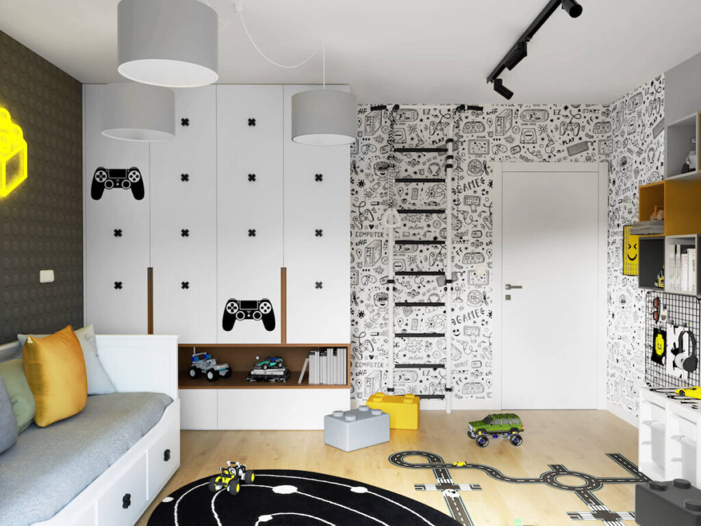 Duża biała szafa ozdobiona naklejkami w kształcie padów i gałkami w kształcie iksów a także czarno biała drabinka gimnastyczna oraz ściana ozdobiona gamingową tapetą w pokoju dla kilkuletniego chłopca