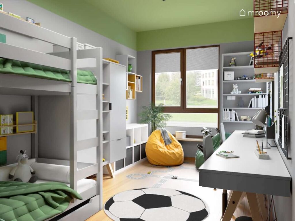 Zielono szary pokój dla dwóch chłopców z łóżkiem piętrowym oraz pojemnymi szafami i regałami a także dwoma biurkami i kolorowym sufitem