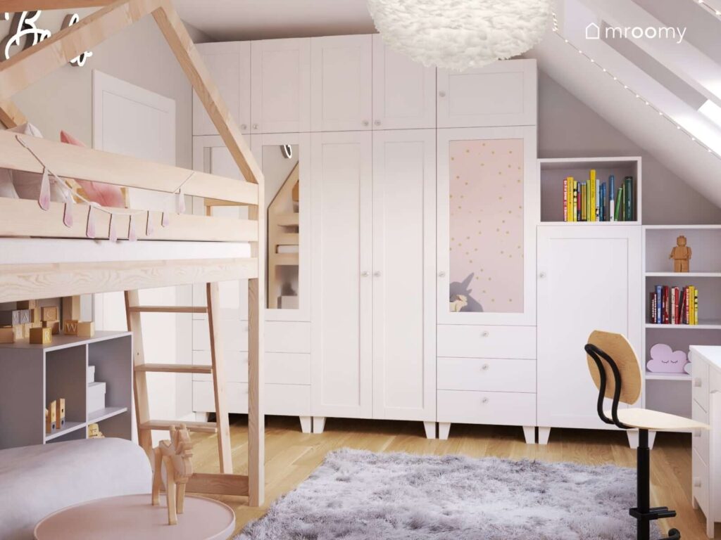 Duża biała szafa z lustrzanymi frontami drewniane łóżko na antresoli oraz szary dywan i ozdobna lampa z piór w pokoju dla kilkuletniej dziewczynki