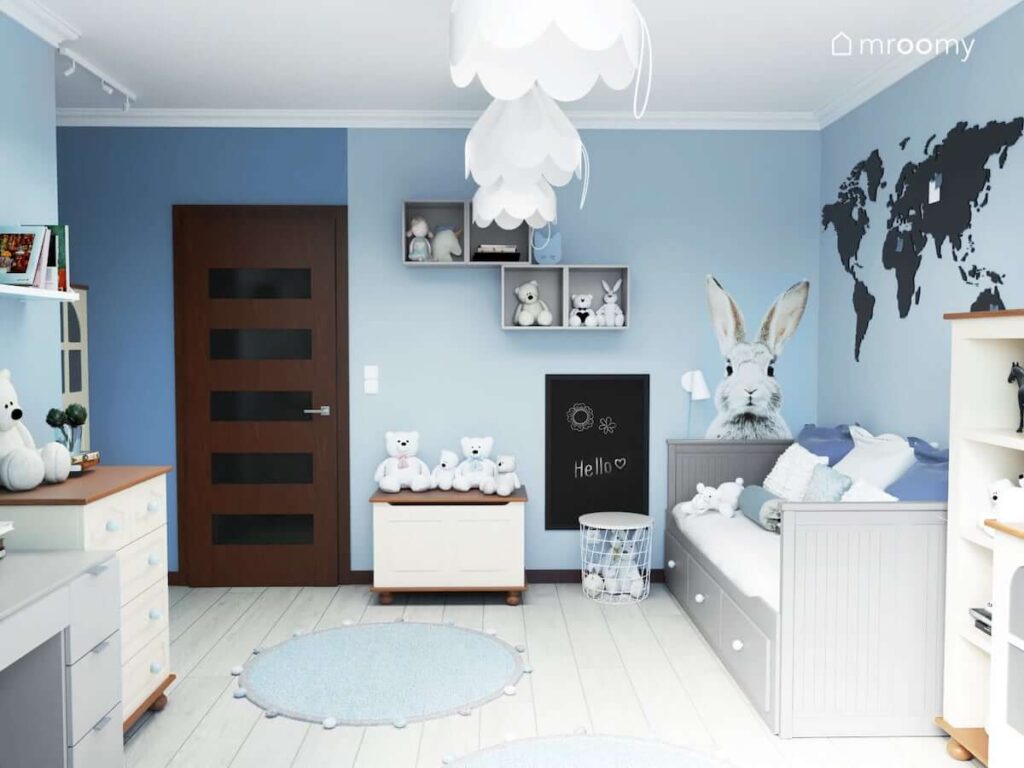 Pokój dla dziewczynki w wieku szkolnym z białymi i szarymi meblami naklejką w kształcie królika na ścianie a także ozdobnymi białymi lampami sufitowymi
