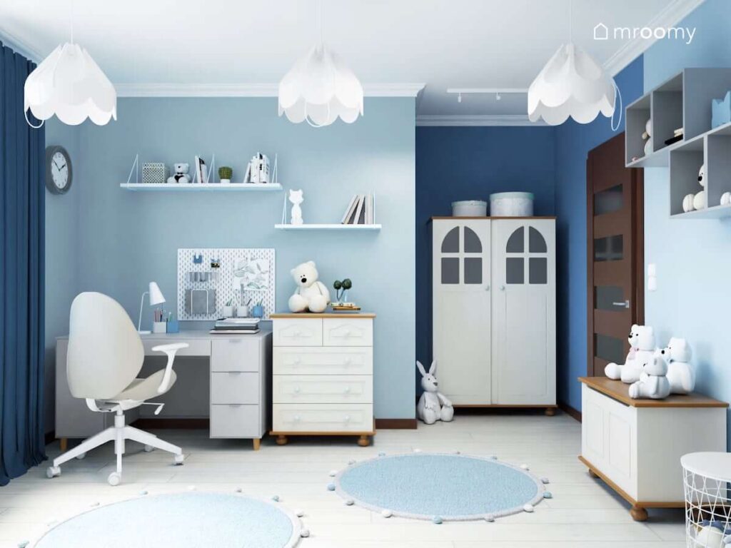 Strefa nauki z biurkiem organizerem i półkami ściennymi oraz szafa oświetlona białymi reflektorami w niebieskim pokoju dla dziewczynki