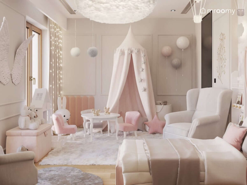 Różowy pokój dla małej dziewczynki z miejscem do zabawy osłoniętym baldachimem oraz stolikiem dziecięcym z krzesełkami z ogonkami oraz ozdobnymi pomponami i kinkietami w kształcie balonów