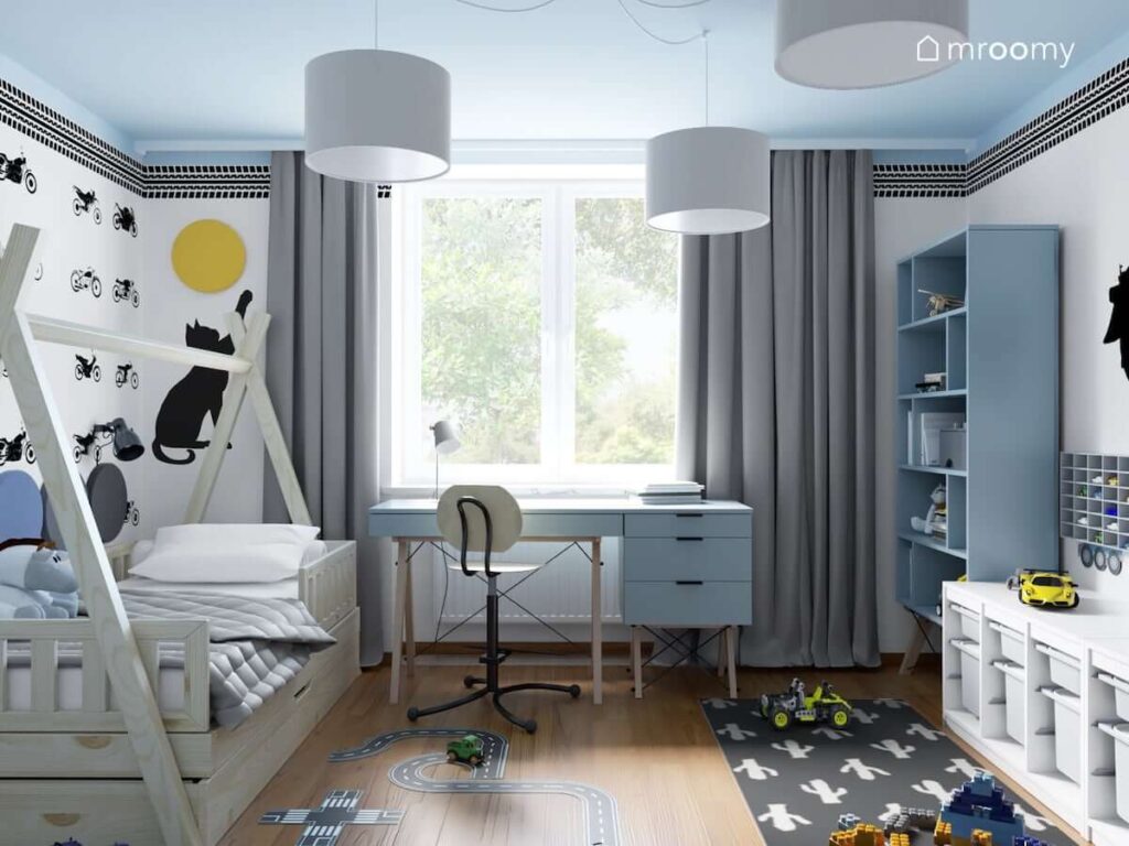 Biało niebieski pokój dla chłopca z łóżkiem tipi niebieskim biurkiem niebieskim regałem oraz dywanem w kaktusy
