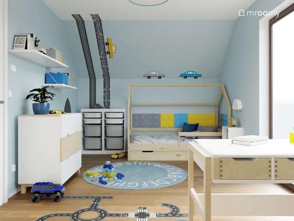Błękitny pokój dla chłopca z drewnianym łóżkiem domkiem oraz ścianami uzupełnionymi naklejkami w kształcie samochodów i śladów opon
