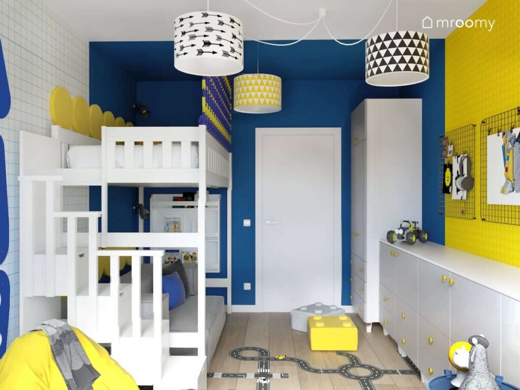 Pokój dla chłopca w wieku szkolnym z niebieskimi żółtymi i białymi ścianami a także łóżkiem na antresoli i dużą białą szafą