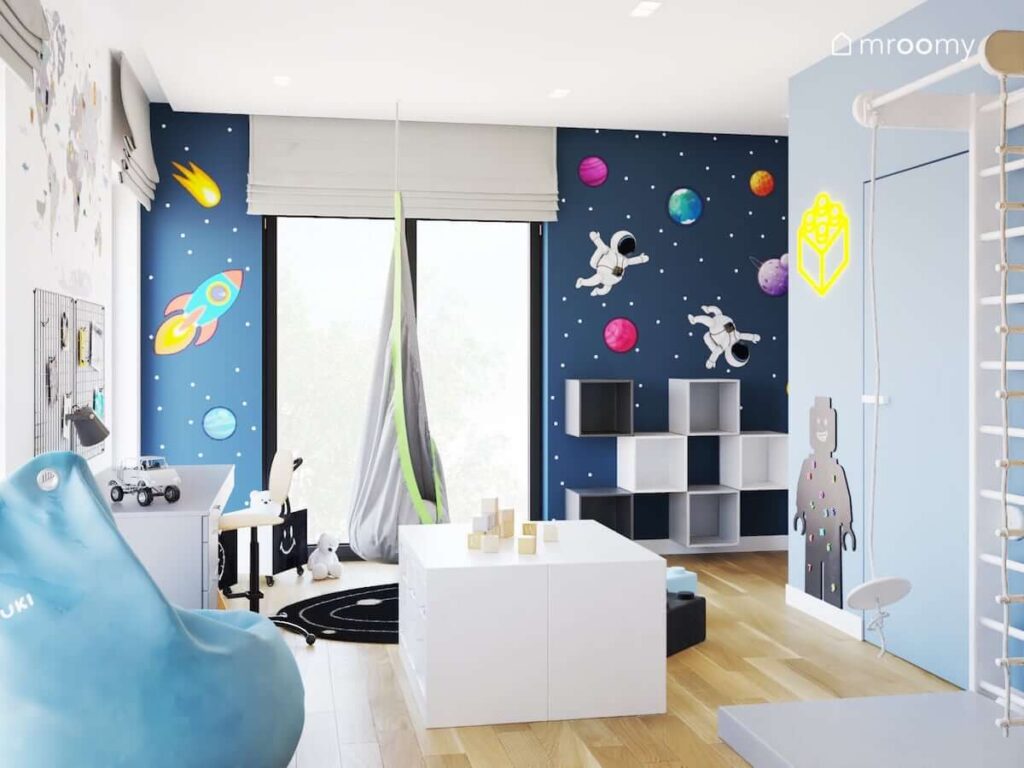 Kosmiczny pokój dla chłopca z fotelem hamakiem białymi i szarymi meblami oraz oryginalnymi naklejkami ściennymi z motywami kosmosu