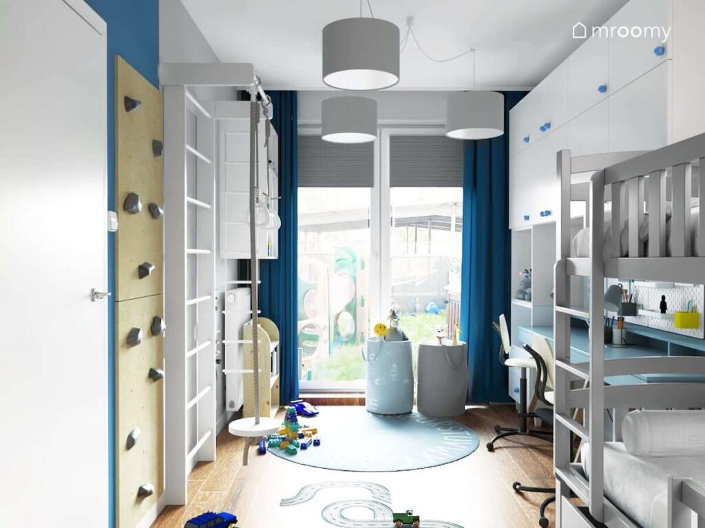 Pokój dla dwóch braci z drabinką gimnastyczną ścianką wspinaczkową koszami na zabawki oraz niebieskim dywanem i naklejką podłogową w kształcie jezdni