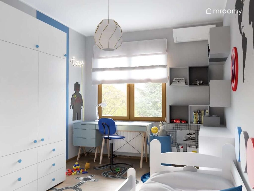Biało szaro niebieski pokój dla chłopca z niebieskim biurkiem i kontenerkiem na drewnianych nogach oraz z wieloma szafkami ściennymi