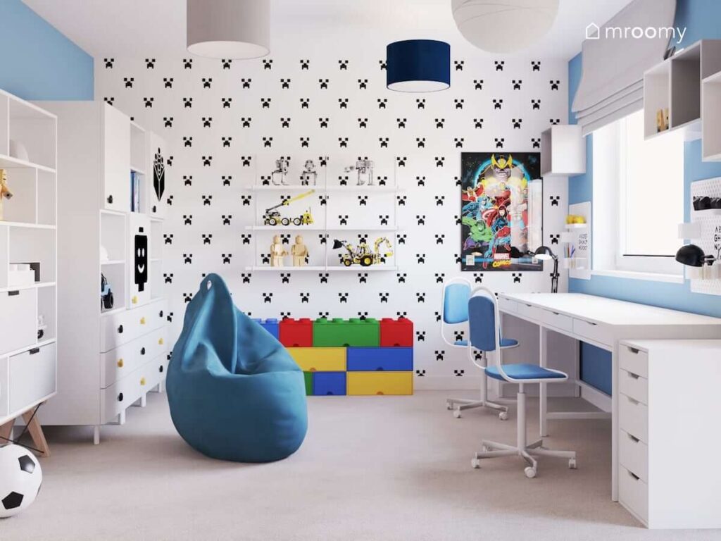 Pokój zabaw dwóch chłopców ozdobiony tapetą z creeperem i wyposażony w dwa regały biurka półki ścienne i kolorowe pojemniki na klocki
