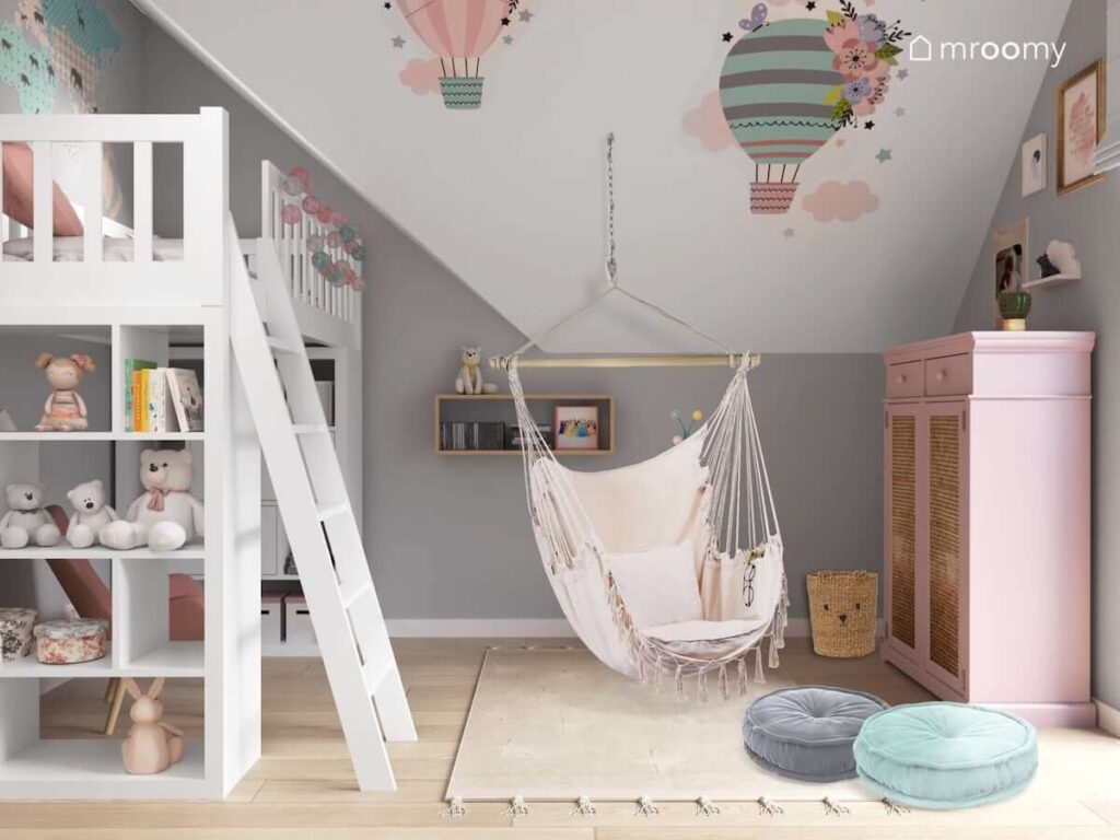Pastelowy pokój dla dziewczynki z łóżkiem na antresoli huśtawką hamakiem oraz skosem ozdobionym naklejkami w kształcie balonów