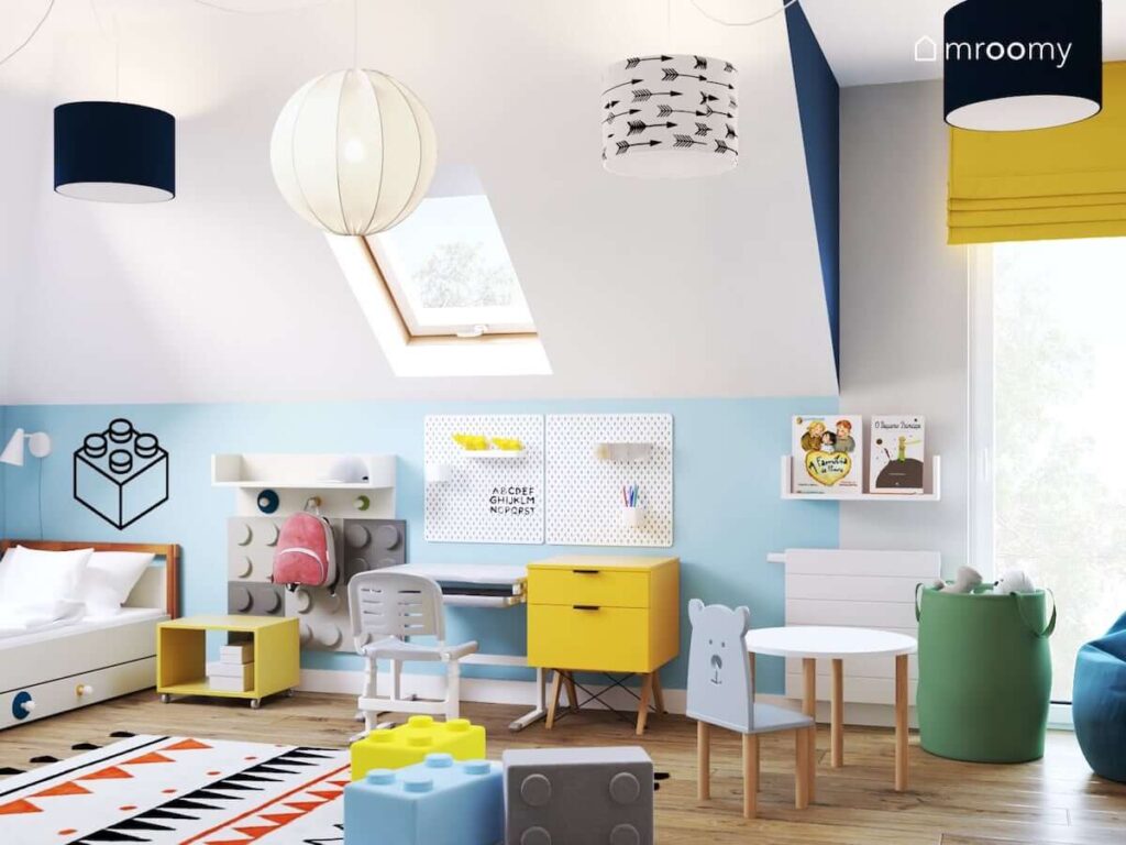 Radosny biało niebieski pokój dla kilkulatka z żółtymi elementami oraz dodatkami z motywem klocków Lego