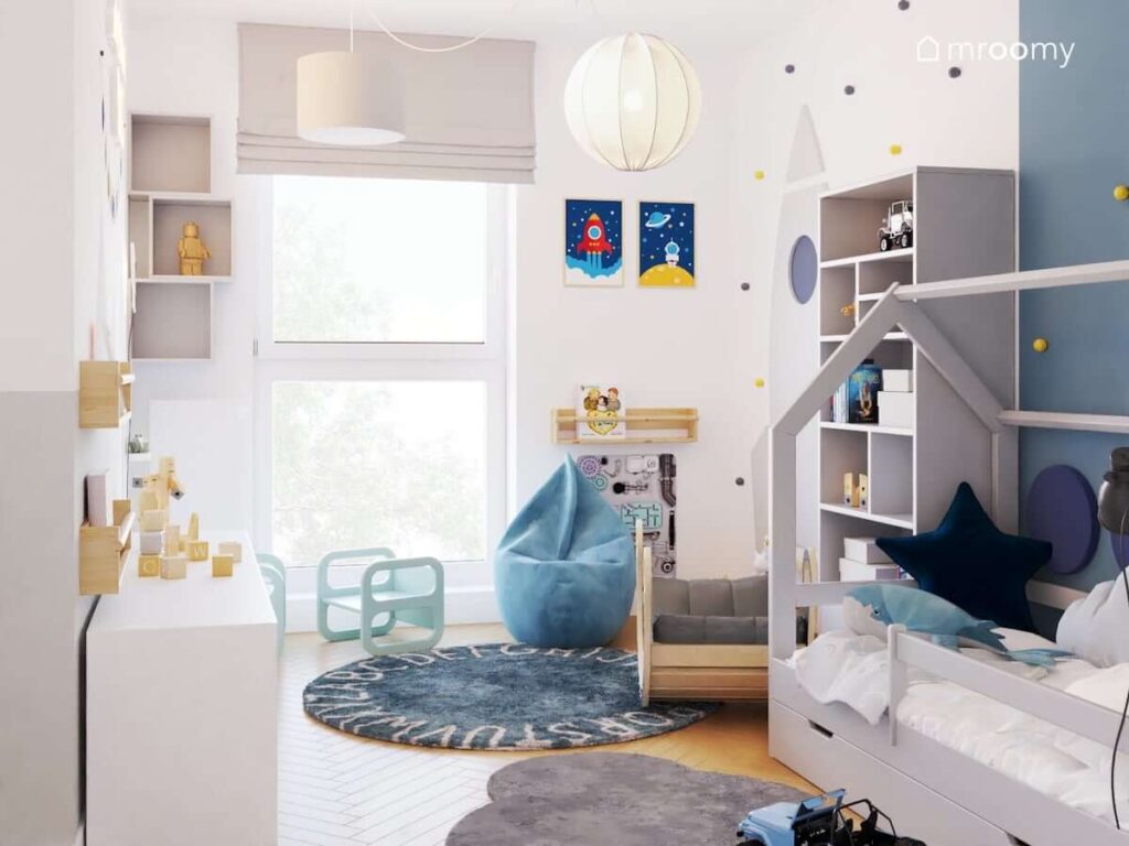 Jasny biało niebieski pokój dla małego chłopca z pufą sako bujakiem i szarymi meblami oraz z kosmicznymi dodatkami