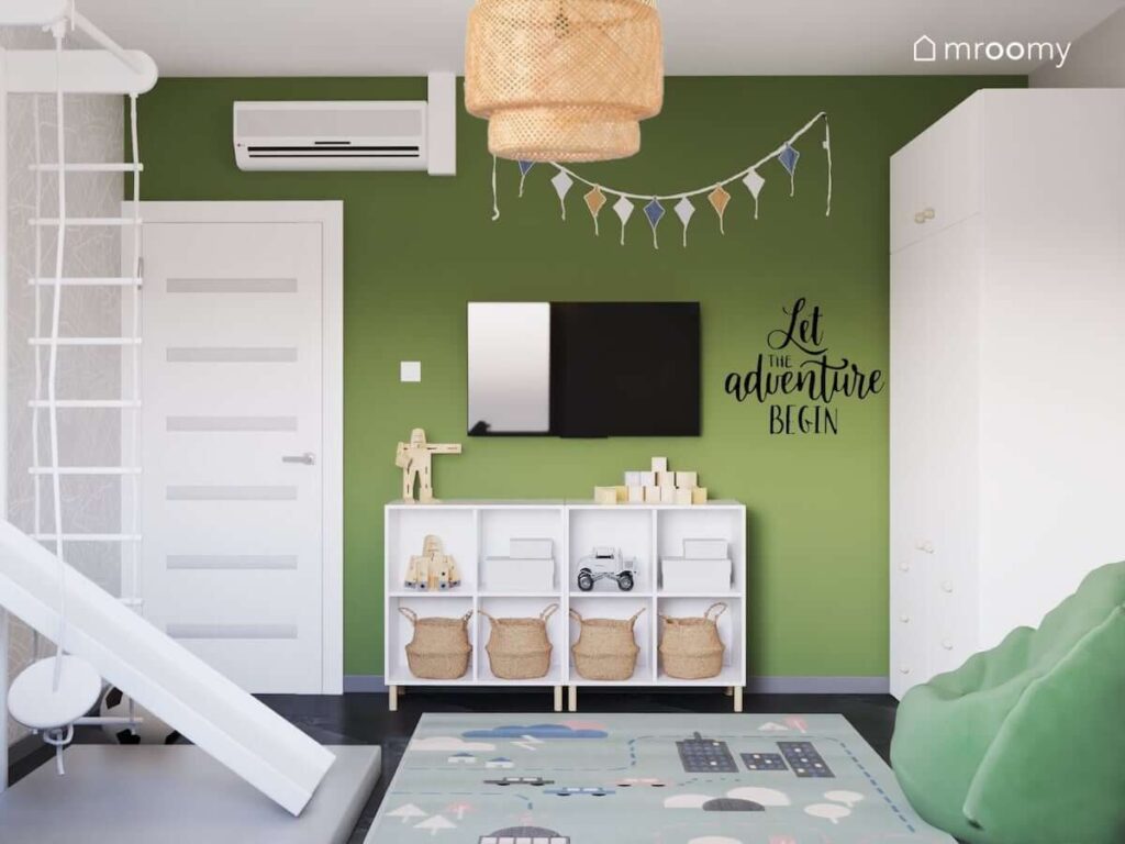 Biało zielony pokój dla chłopca a w nim niski biały regał girlanda na ścianie telewizor i dywan przedstawiający miasto