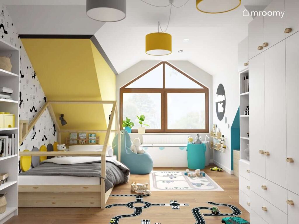 Biało żółty pokój dla chłopca z drewnianym łóżkiem domkiem niebieskimi dodatkami i naklejką podłogową w kształcie jezdni