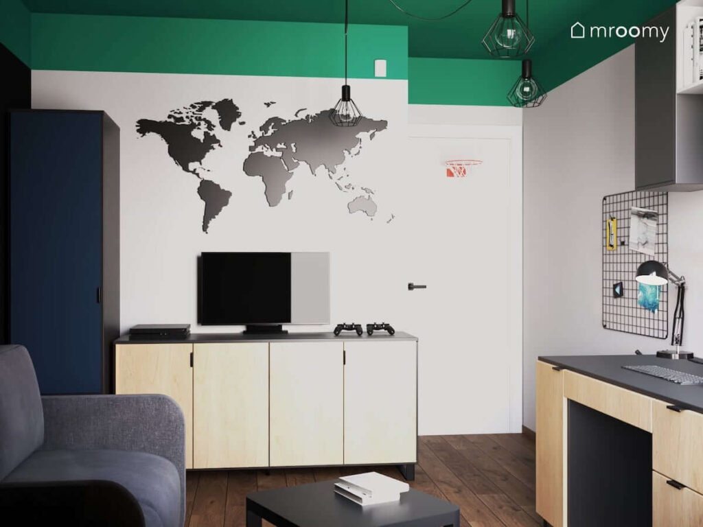 Granatowo czarna szafa drewniano czarna komoda telewizor oraz tablica magnetyczno kredowa w kształcie mapy świata w pokoju dla nastolatka