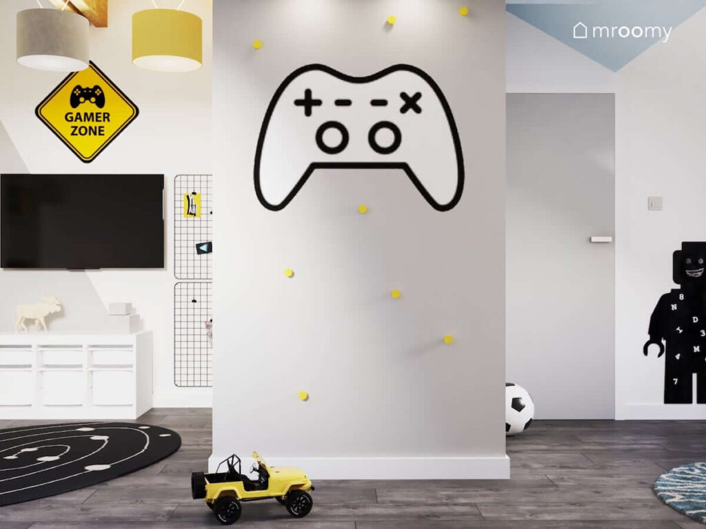 Szara ściana w pokoju dla chłopca ozdobiona żółtymi uchwytami oraz gamingową naklejką