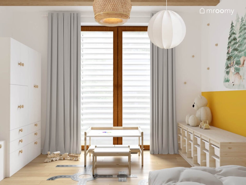 Jasny pokój dla kilkuletniego chłopca a w nim biało drewniane meble szare zasłony i lampa sufitowa z bambusowymi i materiałowymi kloszami