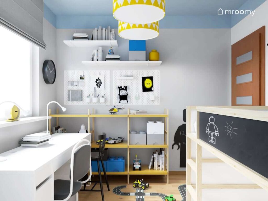 Regał na zabawki organizery i półki ścienne a także lampa sufitowa z biało żółtymi abażurami w pokoju dla dwóch braci