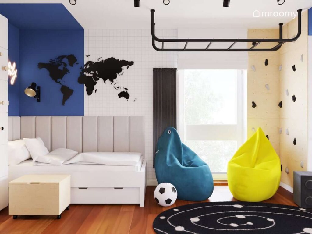 Biało niebieski pokój dwóch chłopców z tablicą kredową w kształcie mapy świata z drabinką gimnastyczną ścianką wspinaczkową i dwoma pufami sako