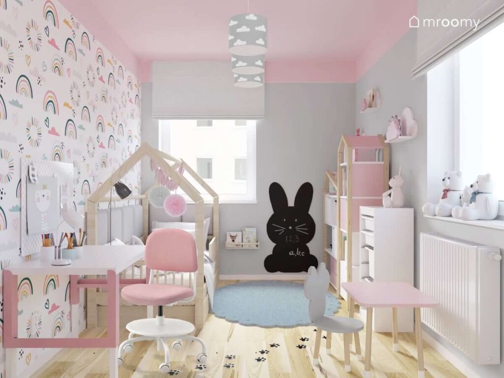Szaro różowy pokój dla dwóch sióstr z drewnianym łóżkiem domkiem tablicą kredową w kształcie królika oraz biało różowym biurkiem