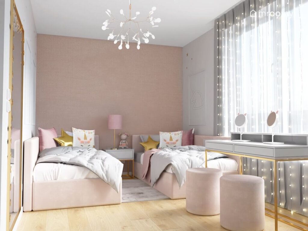 Biało różowy pokój dla dwóch dziewczynek z różowymi łóżkami z dużą liczbą poduszek szarymi biurkami z lusterkami w kocimi uszkami oraz jasnymi siedziskami