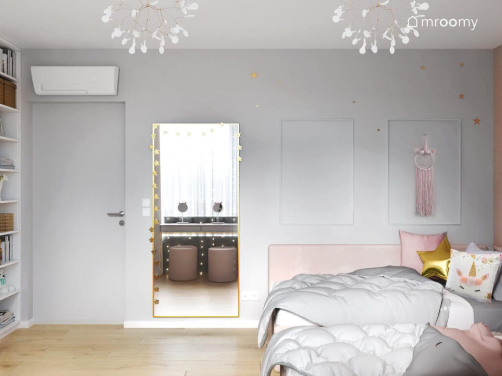 Jasny pokój dla dwóch dziewczynek z dwoma różowymi łóżkami dużym lustrem ozdobionym girlandą gwiezdna oraz łapaczem snów na ścianie