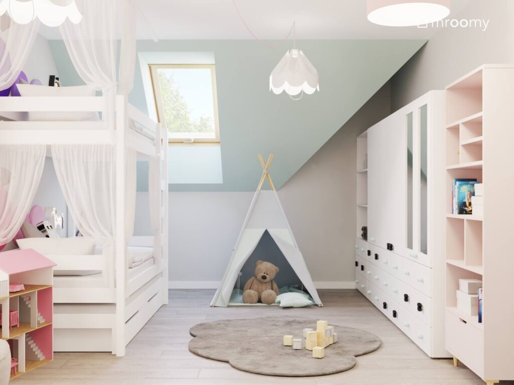 Poddaszowy pokój dla dwóch dziewczynek z łóżkiem piętrowym szafą z lustrzanymi frontami namiotem tipi dywanem w kształcie chmurki oraz białymi lampami sufitowymi