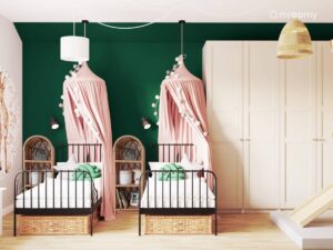 Biało zielony pokój dla dwóch dziewczynek a w nim jasnobeżowa szafa oraz czarne łóżka uzupełnione różowymi baldachimami i girlandami cotton balls i wiklinowymi szafkami