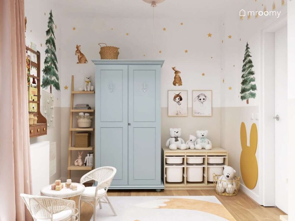 Pokój dla małej dziewczynki z niebieską szafą i drewnianymi regałami a także ze ścianami ozdobionymi motywami leśnymi