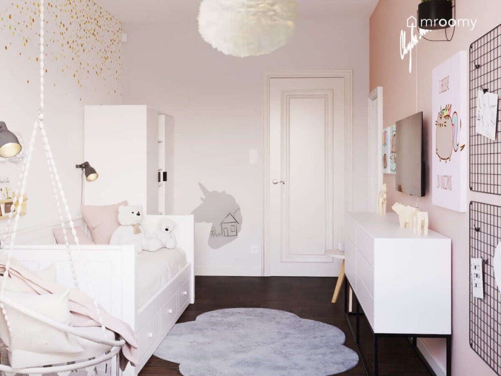 Biało różowy pokój dla kilkulatki z białymi meblami tapetą w złote kropki szarym dywanem w kształcie chmurki i lampą z piór