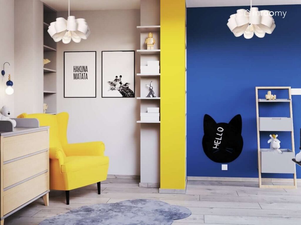 Żółty fotel zabawne plakaty na ścianie oraz tablica kredowa w kształcie głowy kota w kolorowym pokoju dla malutkiej dziewczynki