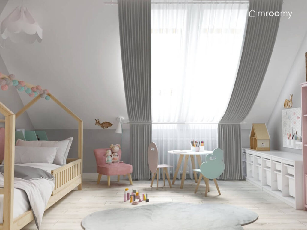Biało szary poddaszowy pokój dla dziewczynki a w nim drewniane łóżko domek różowy fotelik welurowy oraz krzesełka z oparciami w kształcie balona i chmurki
