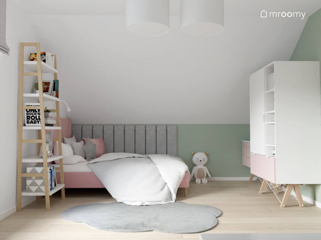 Strefa spania w biało zielonym pokoju dla dziewczynki a w niej różowe łóżko szare panele ścienne i regał w kształcie drabinki