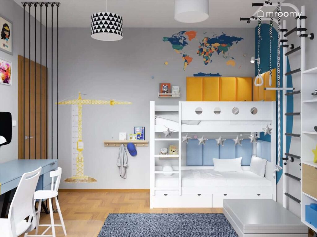 Białe łóżko piętrowe uzupełnione żółtymi i niebieskimi panelami ściennymi oraz kolorową mapą ścienną a także miarka wzrostu w kształcie żurawia w pokoju dla brata i siostry