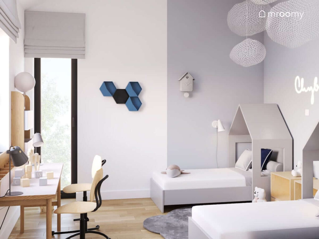 Biało szary pokój dla rodzeństwa z szarymi łóżkami w kształcie domków oraz ozdobnym zegarem ściennym i półkami w kształcie heksagonów